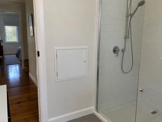 Neat access panel in a painted wall beside a tiled shower room in Botany